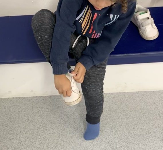 toddler putting on own shoes at Play B C Preschool